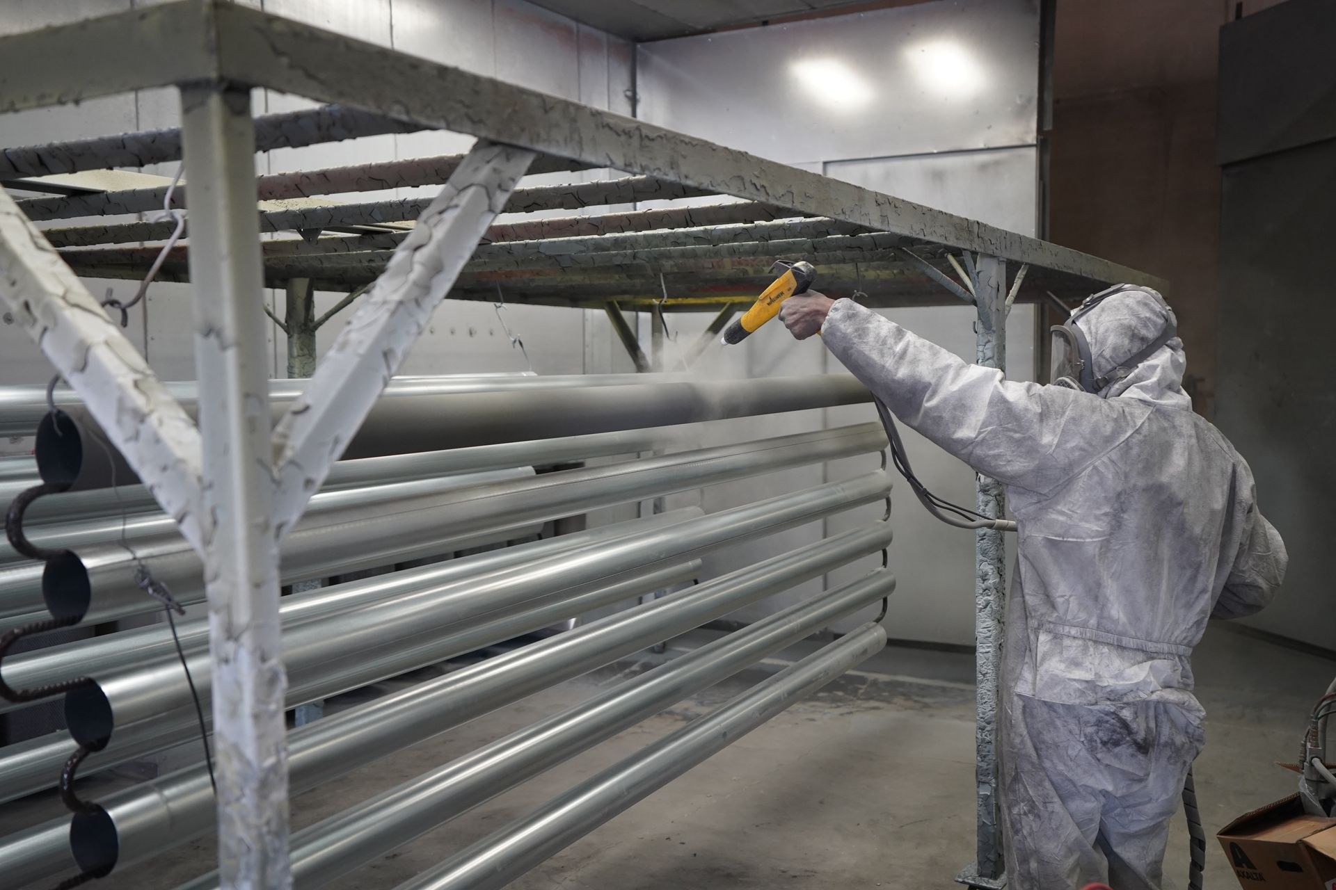Technician performing protective coating on a steel structure in an industrial workshop